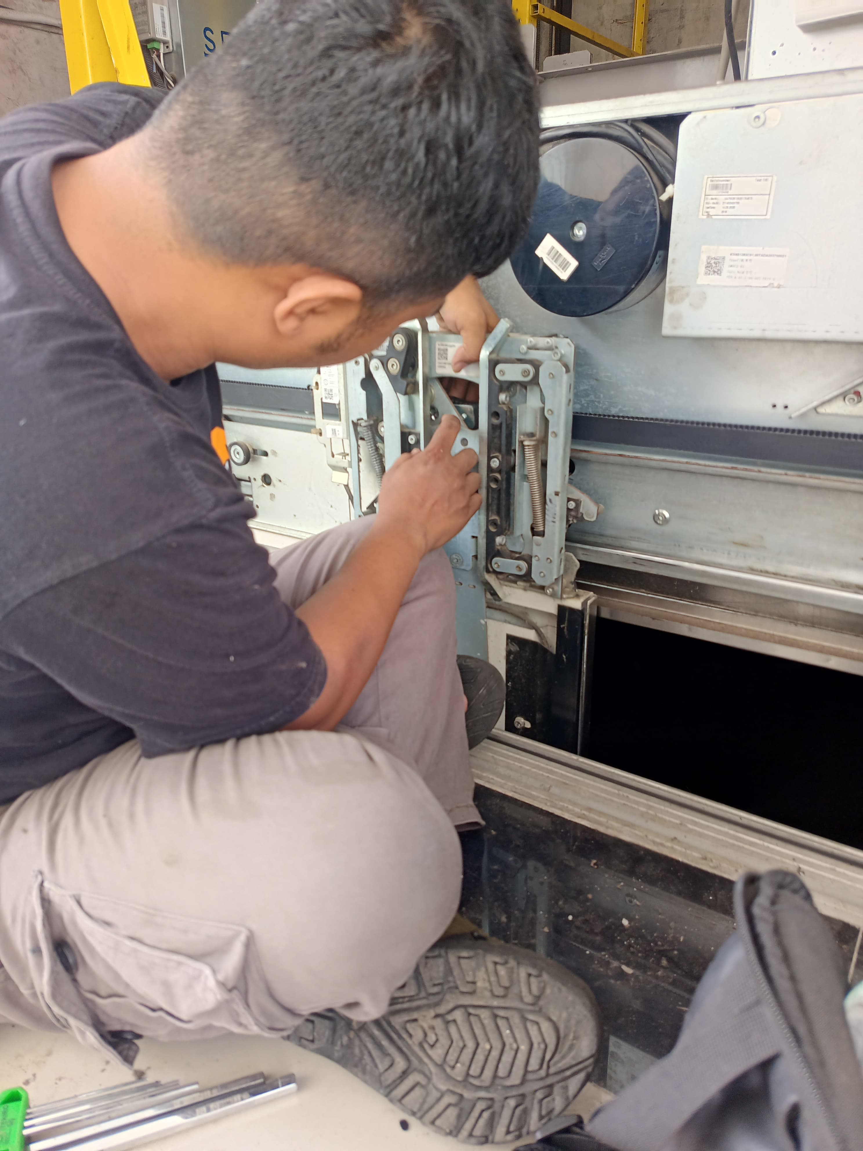 Tim instalasi eskalator modern sedang bekerja di pusat perbelanjaan besar dengan alat dan helm keselamatan warna cerah