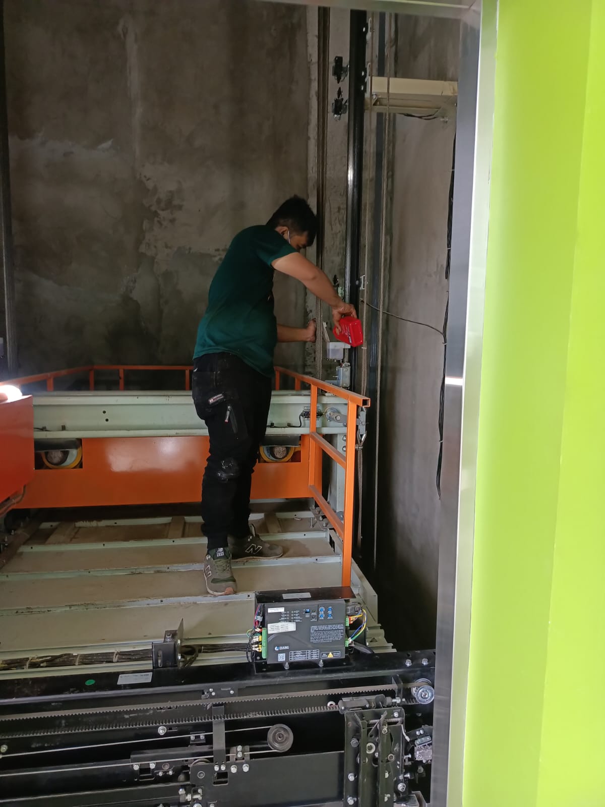 Teknisi sedang melakukan perbaikan lift dengan alat khusus di gedung bertingkat